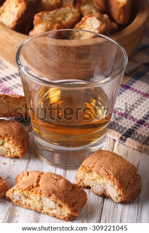 Italian almond biscotti biscuits and sweet wine in a glass closeup on the table. vertical