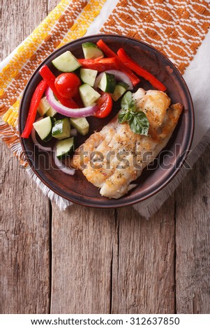 Grilled white fish with fresh vegetables on a plate. vertical view from above, rustic