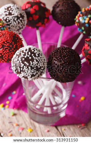 Beautiful chocolate cake pops with colorful candy sprinkles close up in a glass. vertical