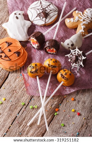 Festive Halloween cake pop and gingerbread cookies close-up on the table. vertical top view