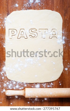 Pasta dough and rolling pin on the wooden table