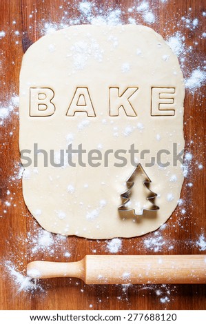 Dough with letters and rolling pin on the wooden table. Kitchen background