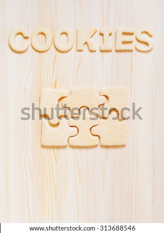 Cookies in the form of puzzles and letters on the wooden table