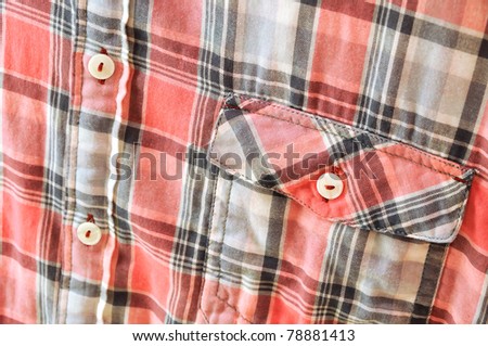 A part of a plaid shirt with pocket and  buttons