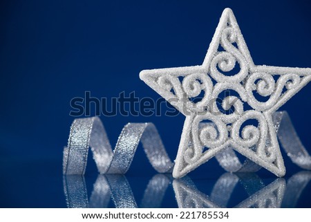 White christmas star with silver ribbon on blue background with space for text. Xmas holiday theme.