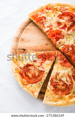 Sliced pizza with tomato, cheese and dry basil on white background top view. Italian cuisine.