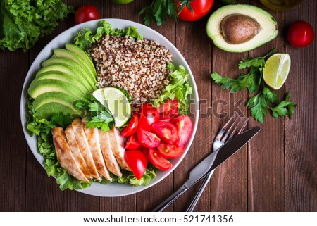 Healthy salad bowl with quinoa, tomatoes, chicken, avocado, lime and mixed greens, lettuce, parsley on wooden background top view. Food and health. Foto d'archivio © 