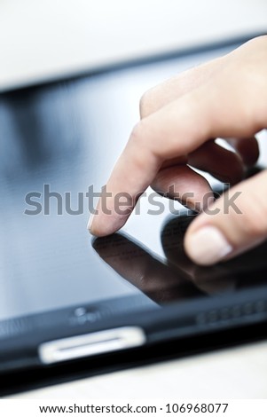 Female hand touching tablet computer screen with finger