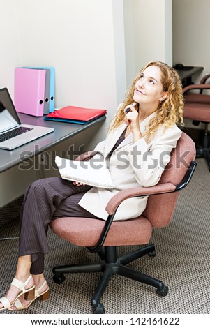 Businesswoman thinking of ideas in office workstation looking up