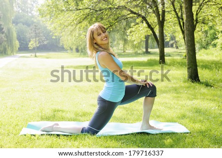 Happy female fitness instructor exercising in green spring park