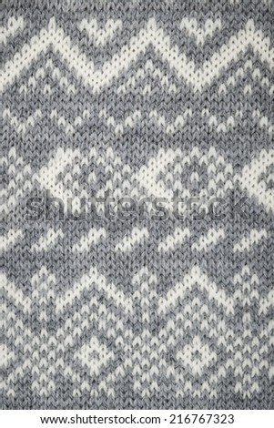 Closeup of knit fabric background with knitted grey and white geometric pattern
