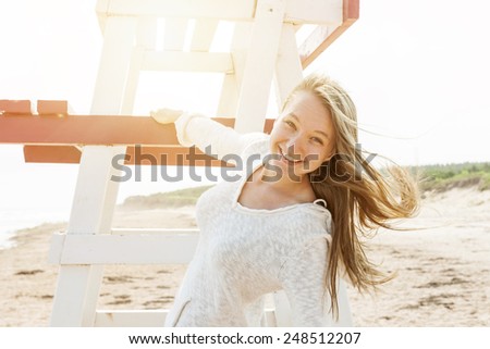 Young carefree woman with lifeguard chair on Atlantic beach in Prince Edward Island, Canada.