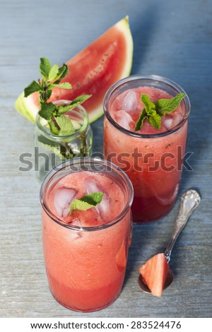 Fresh watermelon slush frozen drinks in two glasses on blue rustic wooden background