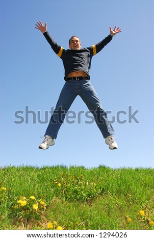 Happy man jumping on green grass