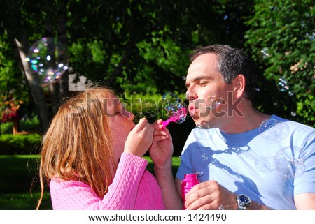 Happy family blowing soap bubbles, father and child