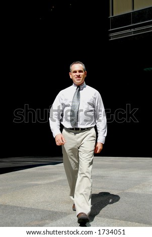 Businessman walking from darkness to light downtown