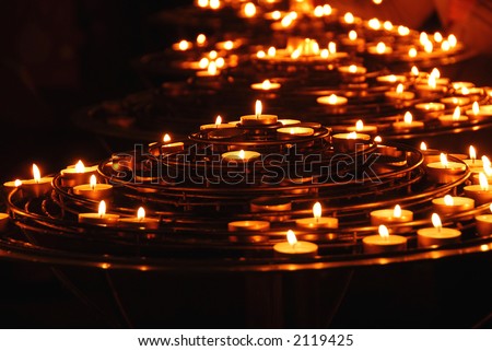 Rows of burning candles inside a cathedral