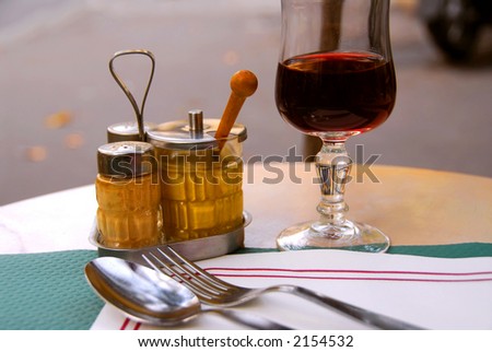 Place setting in outdoor cafe with glass of red wine
