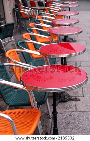 Bright colorful tables in a sidewalk cafe with rain drops