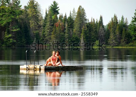 Grangmother and granddaughter sitting on a diving platform on a scenic lake
