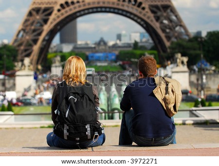Young tourist couple sitting in front of Eiffel tower in Paris France
