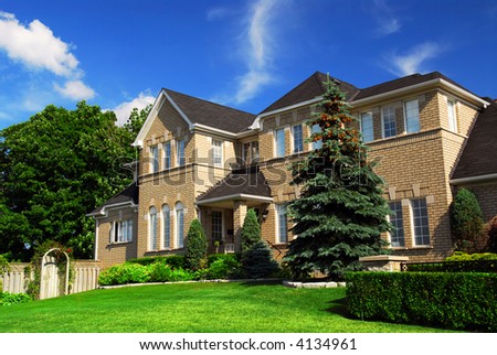 Large upscale residential home with bright green lawn and blue sky