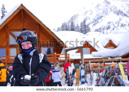 Young girl in ski gear holding a snowball at downhill skiing resort
