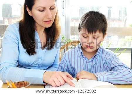 Teacher or tutor helping school boy to study