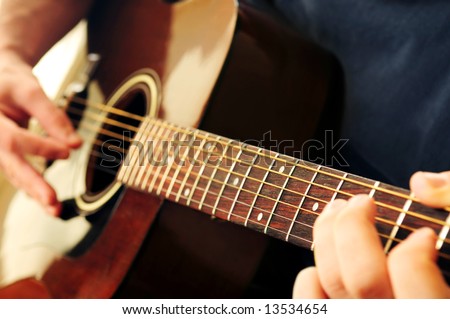 Hands of a person playing an acoustic guitar