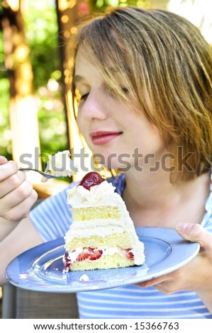 Teenage girl eating a piece of strawberry cake