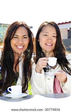 Two girl friends sitting and having drinks at outdoor mall