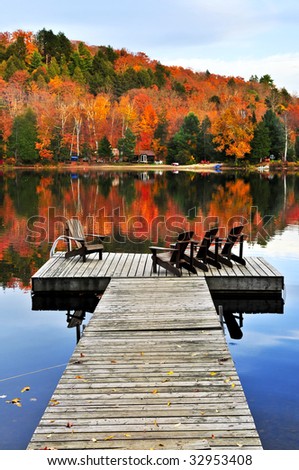 Wooden dock with chairs on calm fall lake