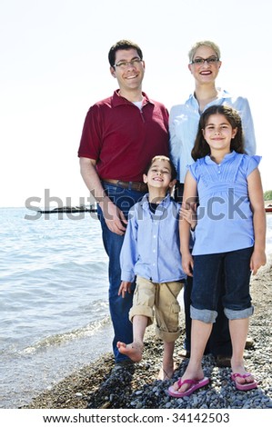 Happy family standing on shore at the beach