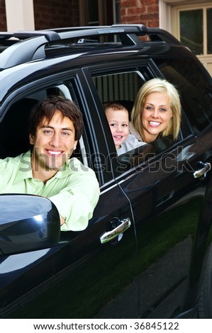 Happy young family sitting in black car looking out windows