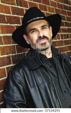 Man with beard in cowboy hat and leather jacket