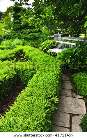 Lush green garden with stone landscaping, hedge, path and bench