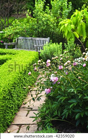 Lush green garden with stone landscaping, flowers, hedge and bench