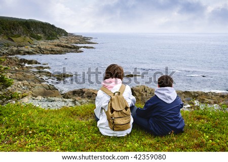 Children looking at coastal view of rocky Atlantic shore in Newfoundland, Canada