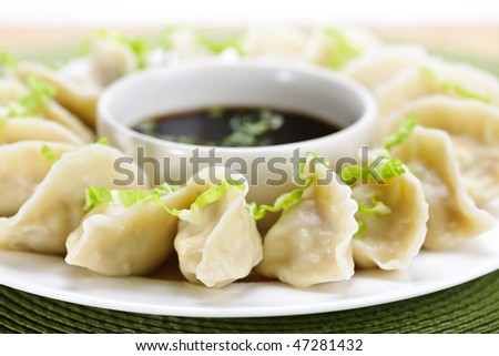 Closeup on plate of steamed dumplings with soy sauce