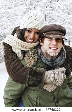 Portrait of couple having piggyback ride outdoors in winter