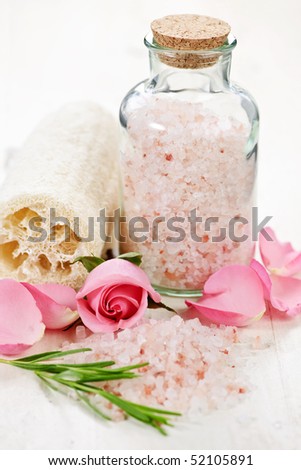 Pink bath salts in a glass jar with flowers and herbs