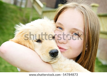 Portrait of smiling teenage girl holding golden retriever puppy