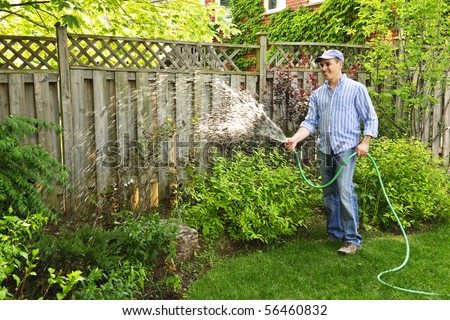 Man watering the garden with hose in backyard
