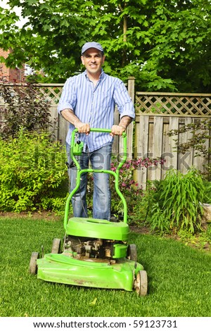 Man with lawn mower in landscaped backyard