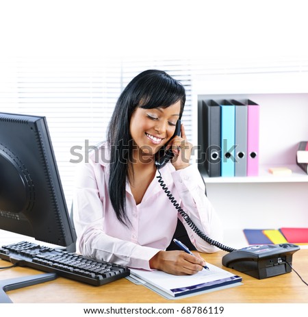 Smiling young black business woman on phone taking notes in office