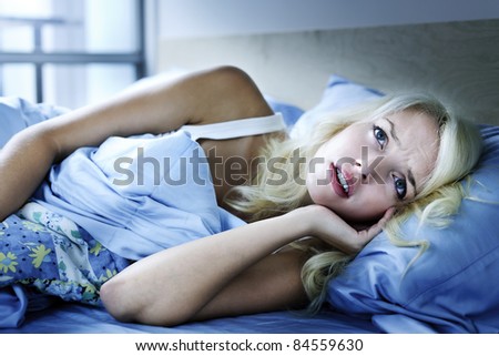 Worried young woman laying in bed sleepless at night