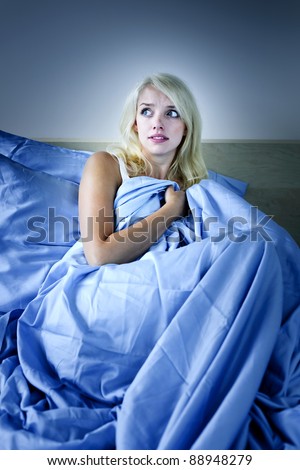 Sleepless blonde woman scared at night in bed
