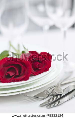 Romantic table setting for two with roses plates and cutlery