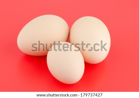 Three brown eggs in red background.
