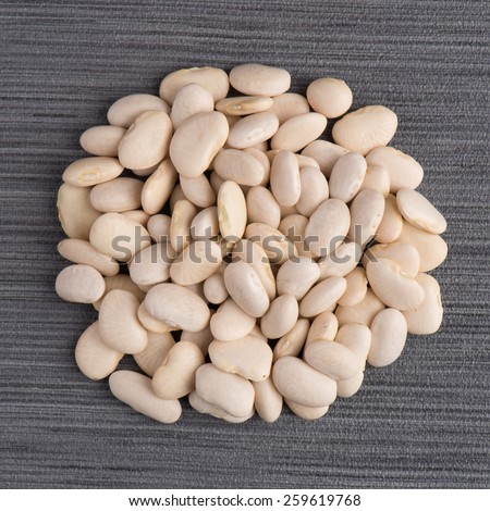 Top view of circle of white beans against white vinyl background.